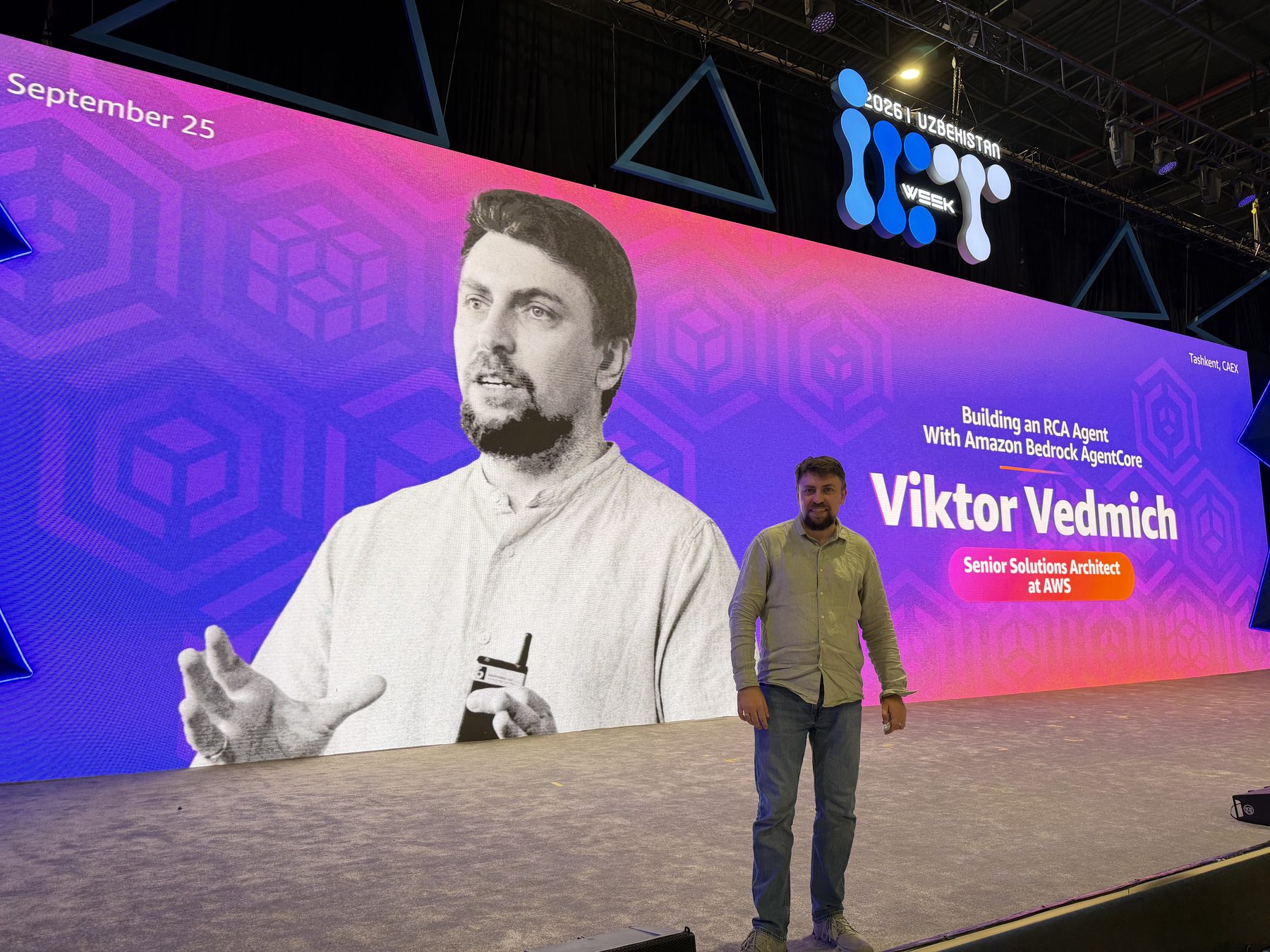 Viktor Vedmich on the CAEx stage in front of the screen announcing the talk Building an RCA Agent with Amazon Bedrock AgentCore, September 25