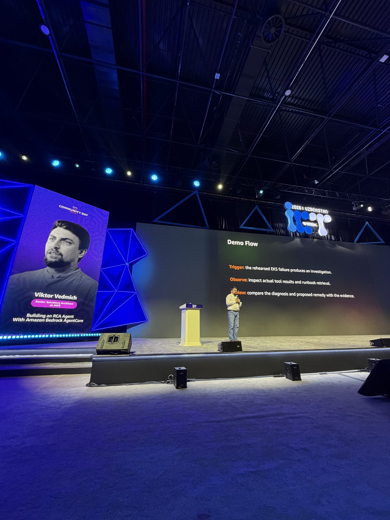 Wide view of the Main Hall stage at CAEx during the talk, with the speaker banner and the Demo Flow slide